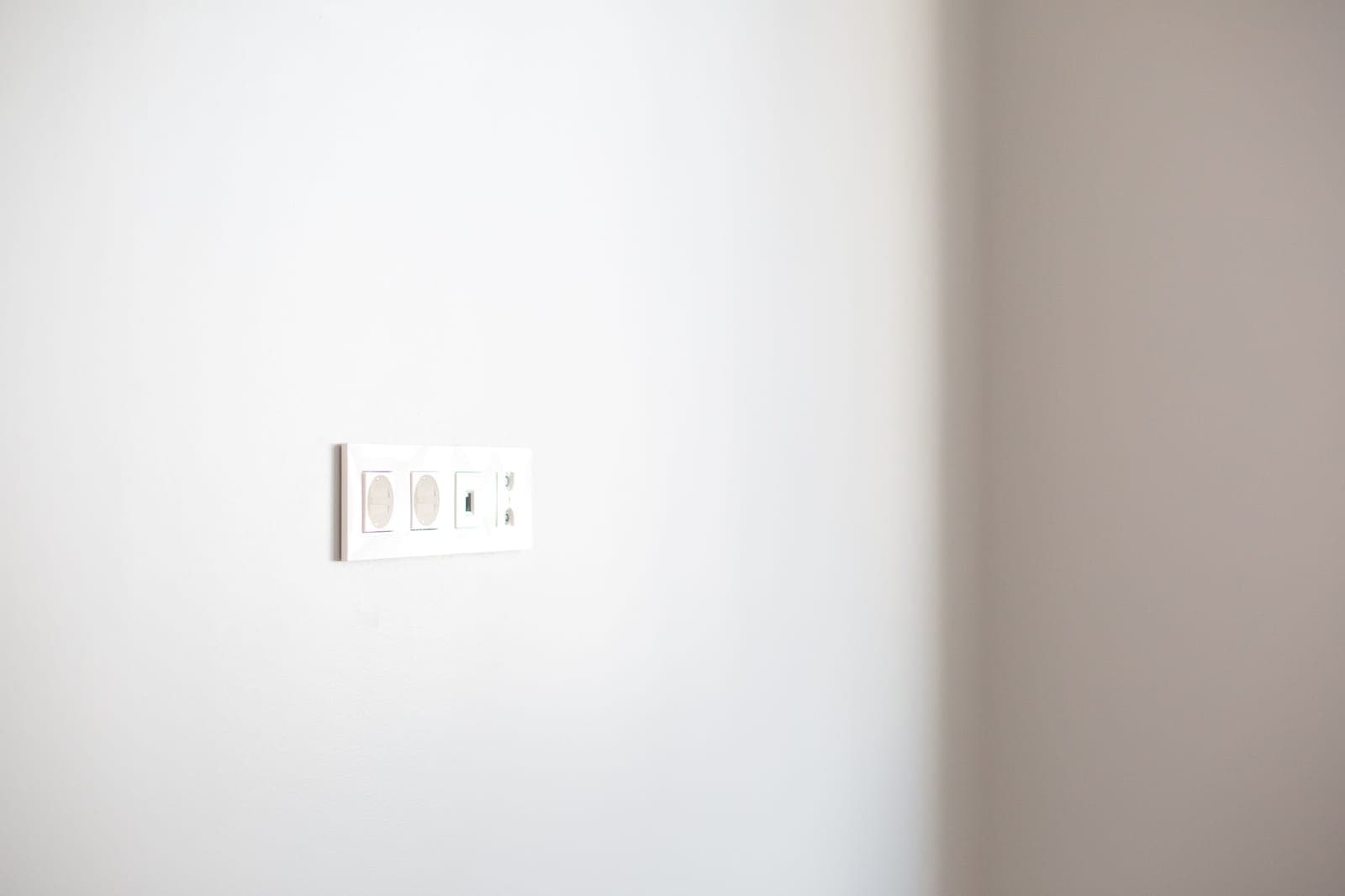 A plain wall socket on an empty painted wall