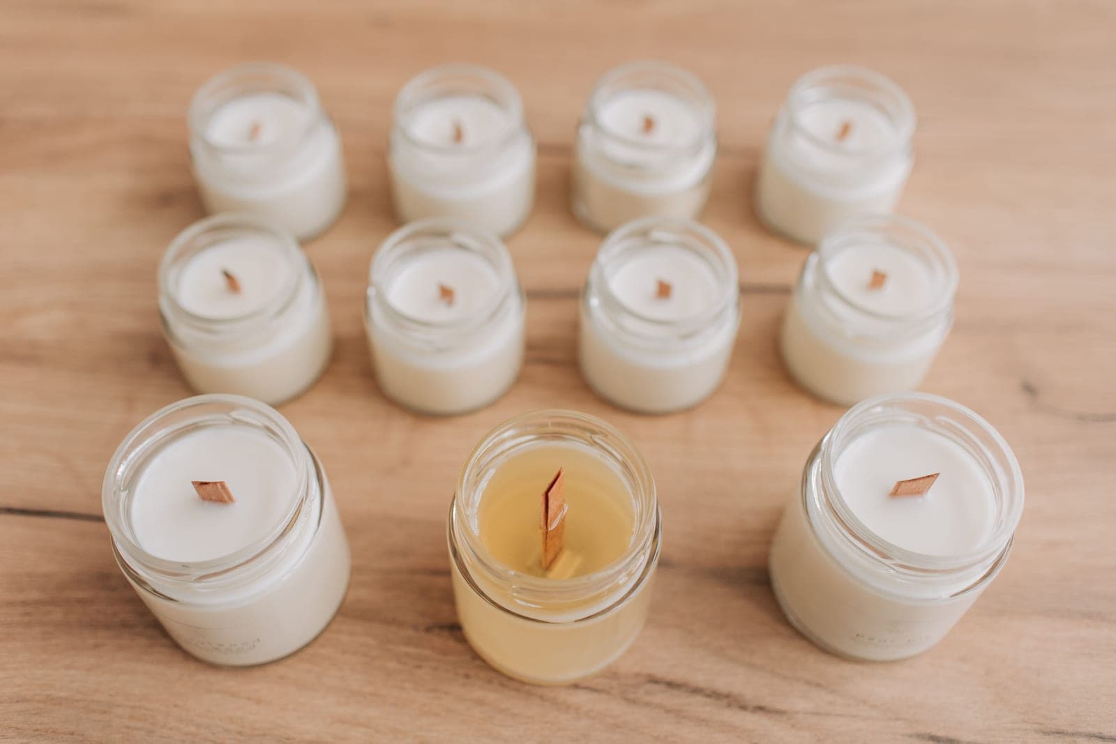 Unlit jar candles with wooden wicks arranged on a wooden table