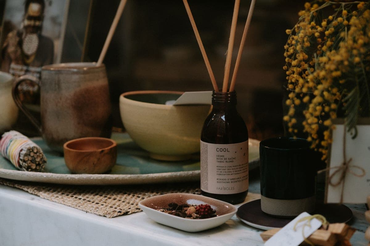 A reed diffuser bottle and small ceramics arranged on a table
