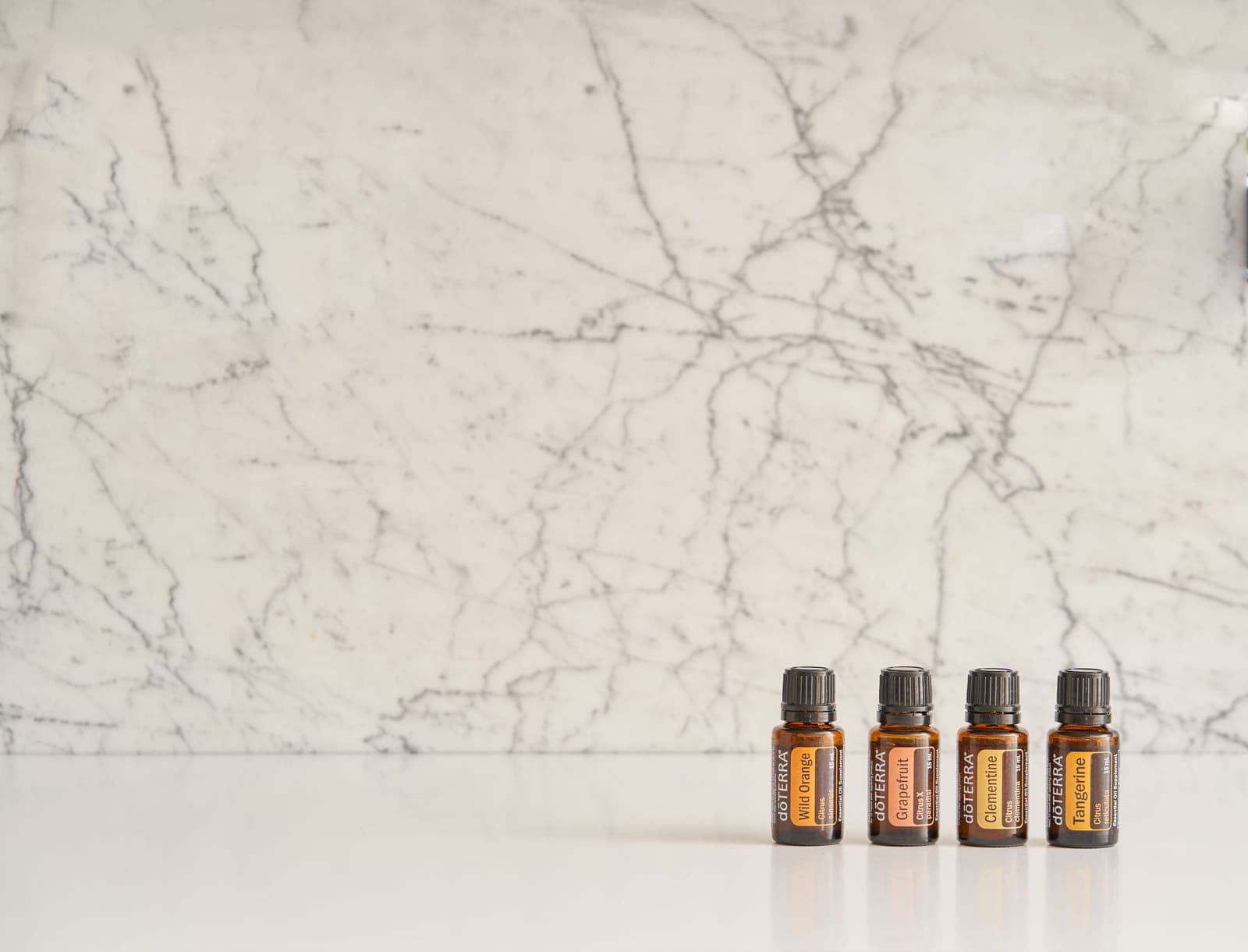 Small brown essential oil bottles on a white marble surface
