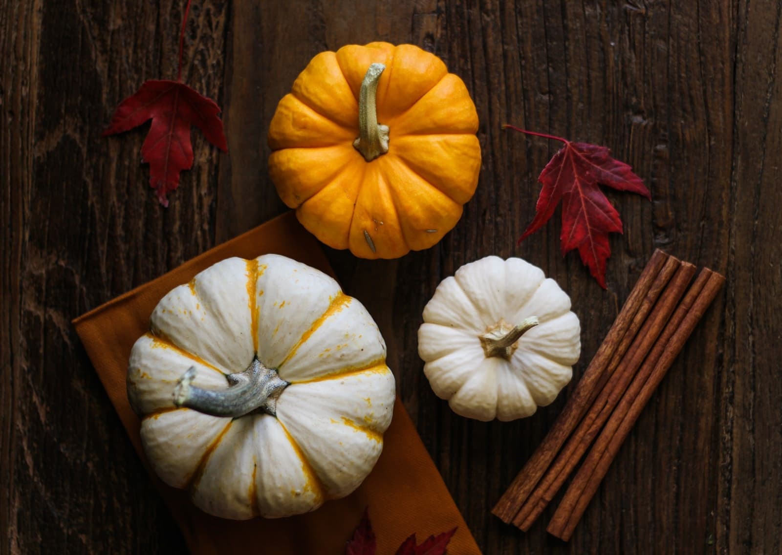 Autumn leaves and small pumpkins arranged on a wooden table