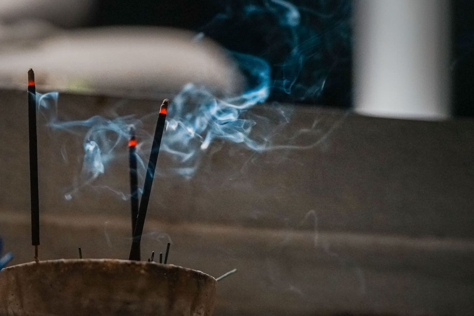 Incense sticks burning, with smoke rising in a dark room
