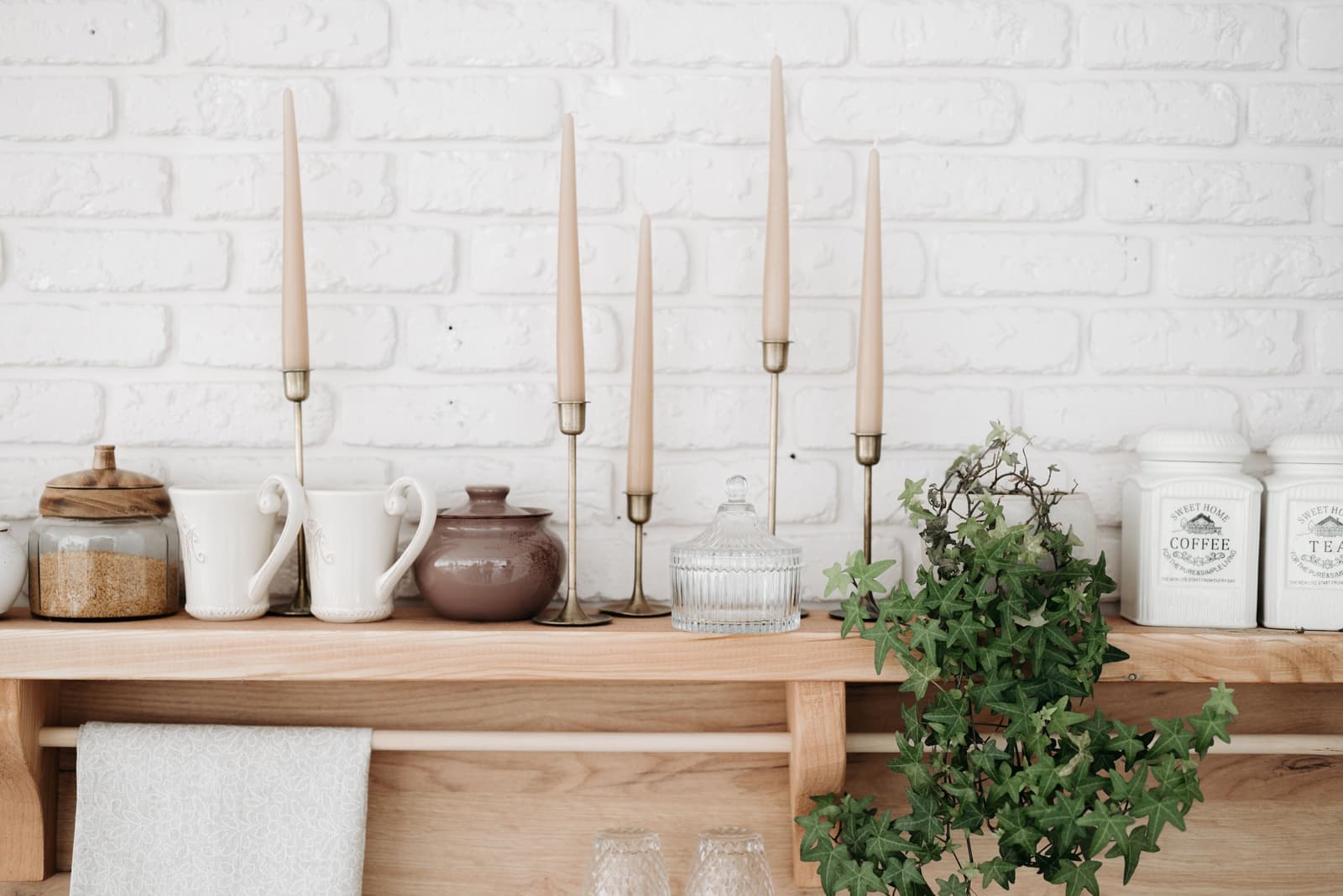 Candles in glass jars and ceramic containers on a wooden shelf