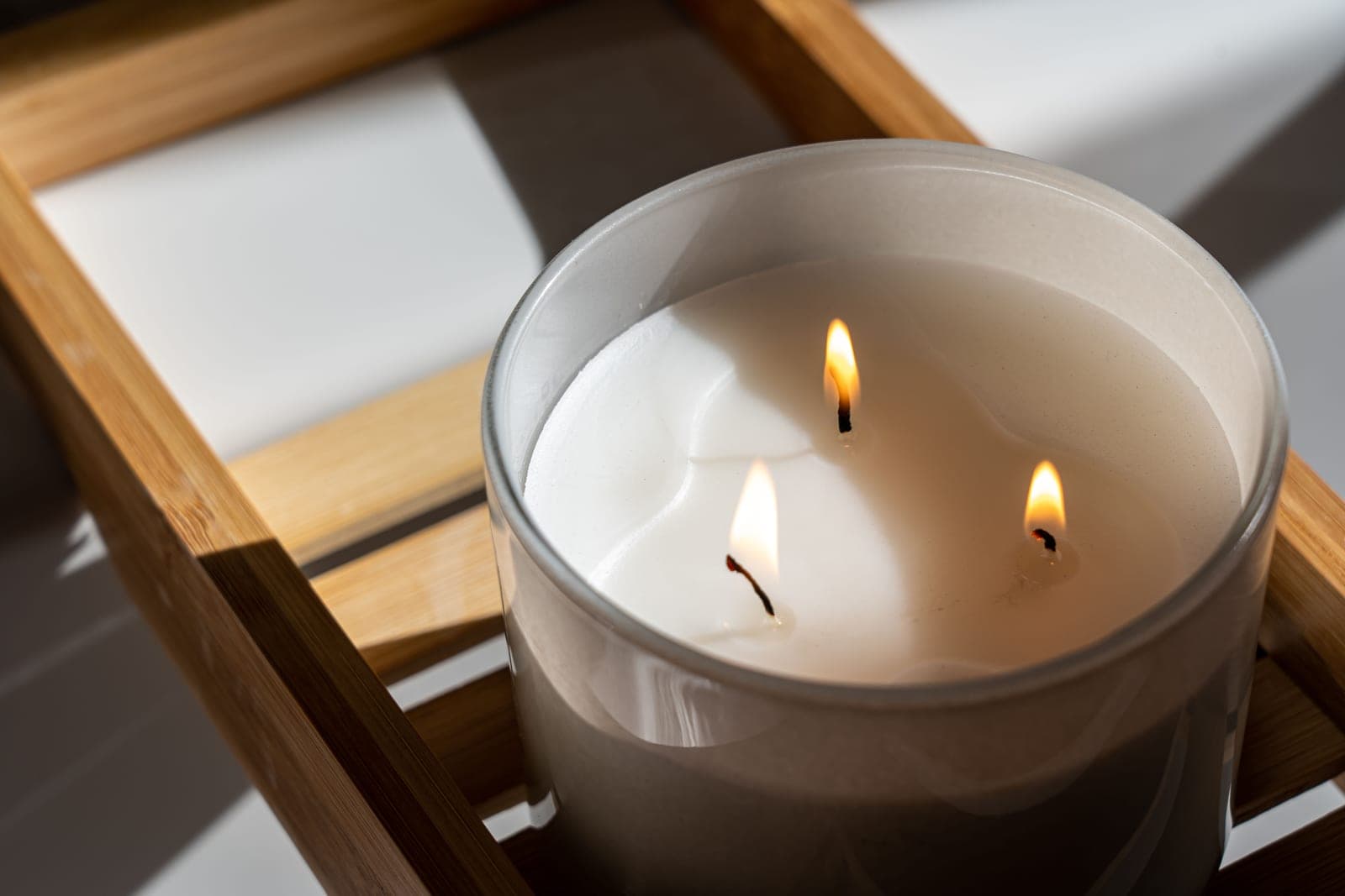 A large three-wick jar candle unlit on a wooden surface