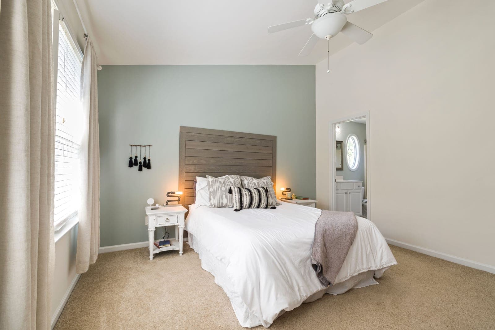 A lamp on a nightstand beside a made bed