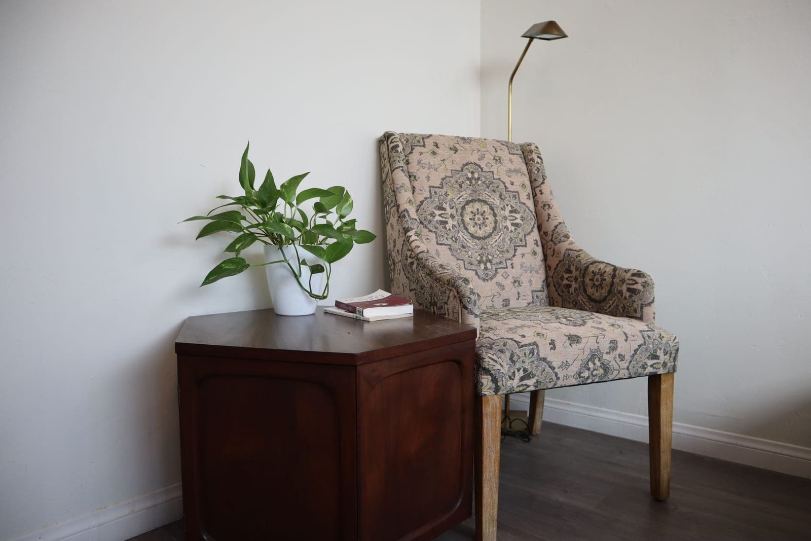 An armchair and a side table with a potted plant in a living room corner